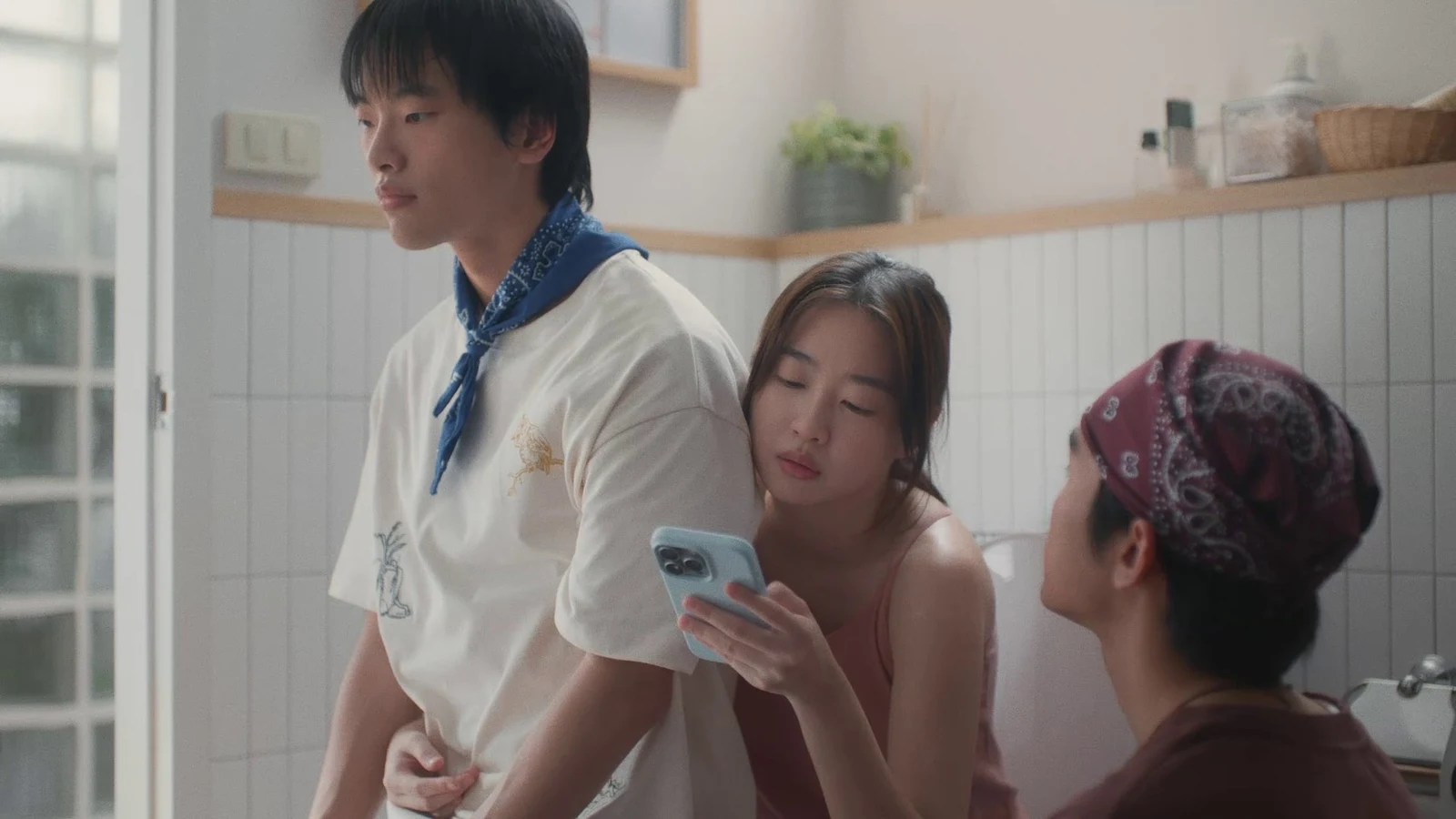 Pramy reklamının banyo sahnesinde iki insan oyuncu ve telefon tutan kadın.